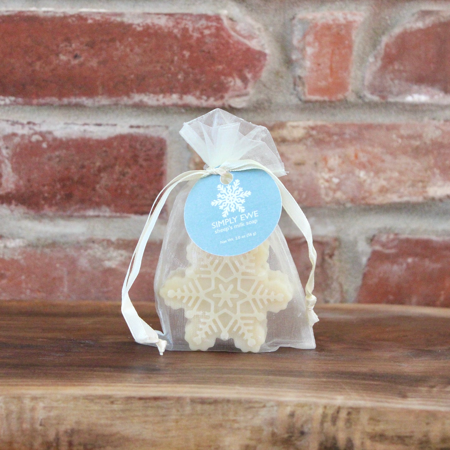 Snowflake-shaped Simply Ewe Sheep's Milk Soap on a wooden board with a brick background.