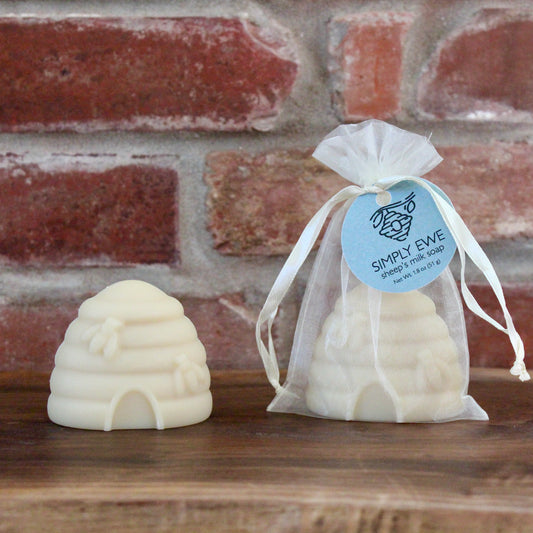 Beehive-shaped sheep's milk soap on a wooden board with a brick background.